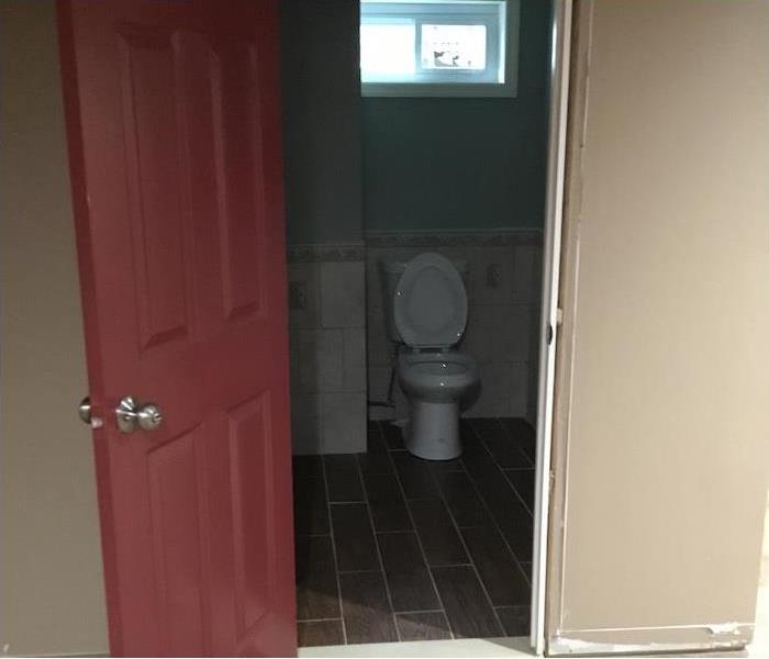 bathroom cleaned with tile floor and red door