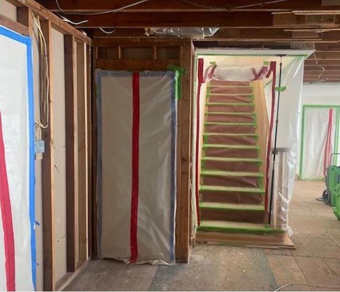 Basement with sealed walls and stairs, new drywall and subfloors, and SERPVRO drying equipment