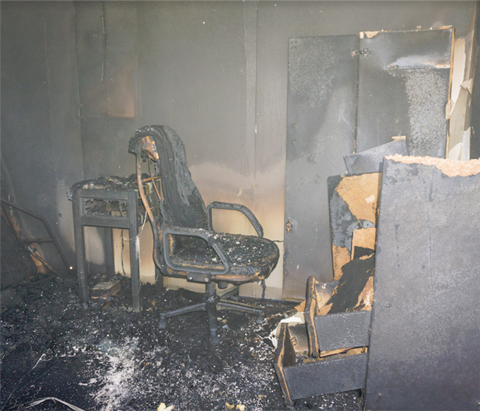a fire damaged room with soot covering everything and charred debris everywhere